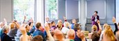 Overzicht van de zaal op de bijeenkomst 9 oktober. Een aantal deelnemers steekt de vingers omhoog