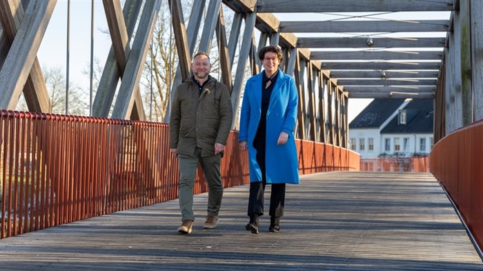 Wethouder Van Overdijk en beleidsmedewerker Van Hout lopen over de nieuwe fietsbrug.